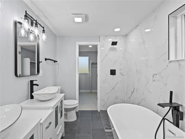 a spacious bathroom with a granite countertop sink toilet a mirror and shower