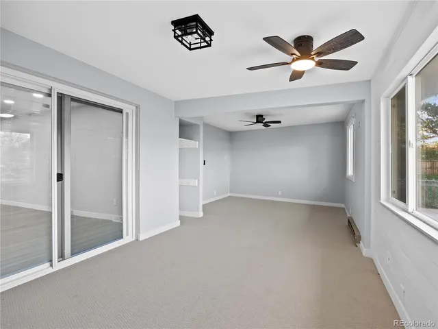 an empty room with windows and fan