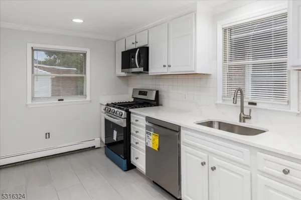 a kitchen with granite countertop white cabinets and stainless steel appliances