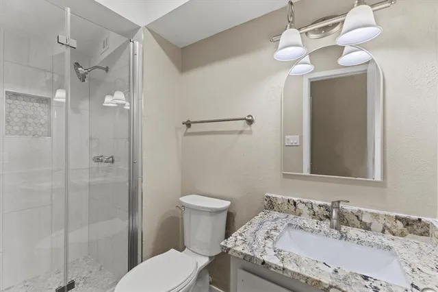 a bathroom with a granite countertop sink a toilet and shower