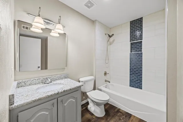 a bathroom with a granite countertop sink a toilet and shower
