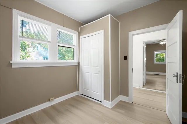 a view of a hallway with wooden floor and a bathroom