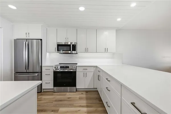 a kitchen with granite countertop white cabinets and stainless steel appliances