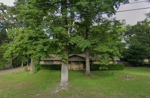 a view of a wooden house with a big yard and large trees