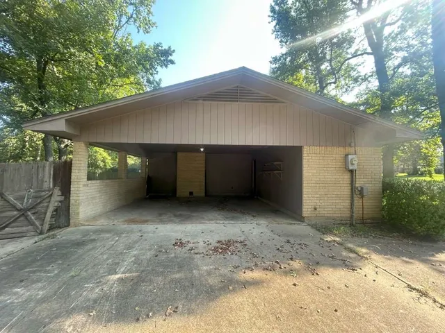 a view of a house with a small yard and a large tree