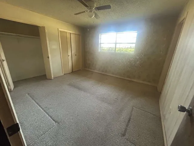 an empty room with a window and a fan
