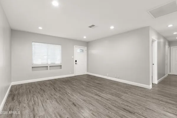 a view of empty room with wooden floor and fan