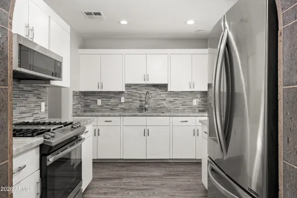 a kitchen with stainless steel appliances granite countertop a stove a refrigerator and a sink