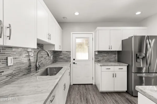 a kitchen with a refrigerator sink and white cabinets