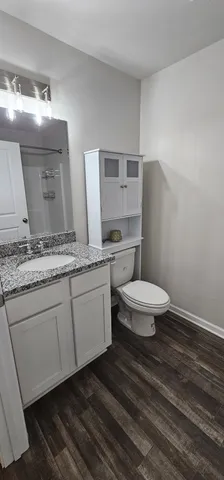 a bathroom with a granite countertop toilet a sink and a mirror
