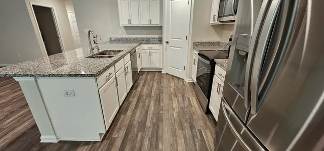 a kitchen with kitchen island wooden floors appliances and cabinets