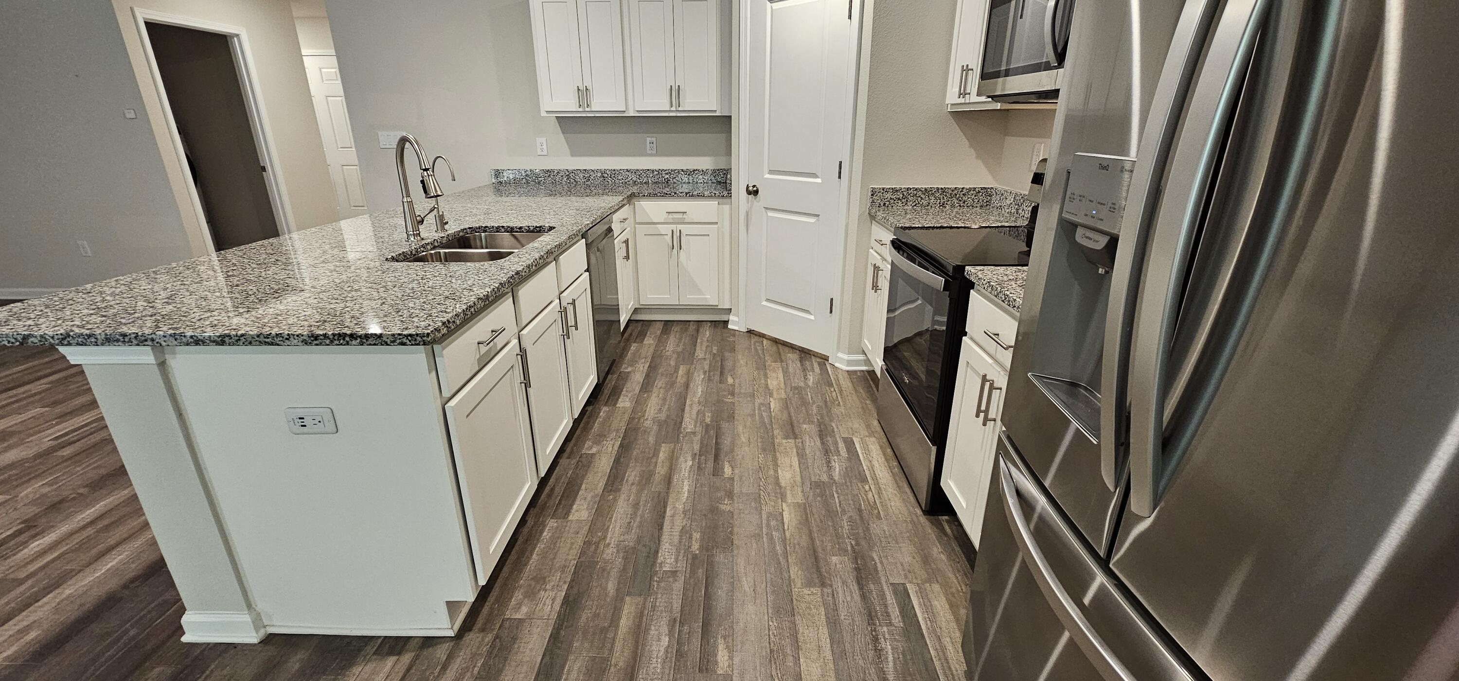 460 Riverwalk Circle Freeport, FL 32439 - Photo 7 of 25 a kitchen with sink a refrigerator a stove and wooden floor
