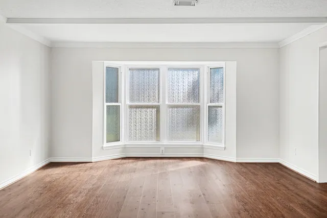 a view of an empty room with wooden floor and a chandelier fan