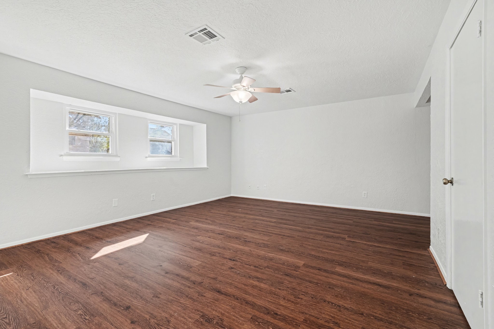 6910 Chancellor Drive Spring, TX 77379 - Photo 16 of 41 a view of an empty room with wooden floor and a ceiling fan