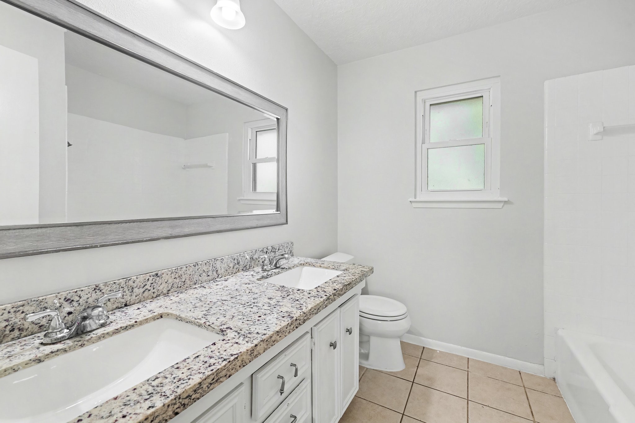6910 Chancellor Drive Spring, TX 77379 - Photo 26 of 41 a bathroom with a granite countertop sink a toilet and a mirror