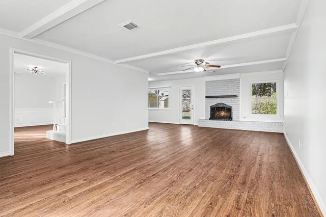 a view of an empty room with wooden floor and a ceiling fan