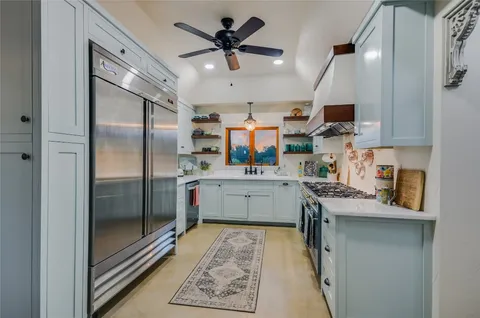 a kitchen with stainless steel appliances kitchen island granite countertop a refrigerator a sink a stove and white cabinets