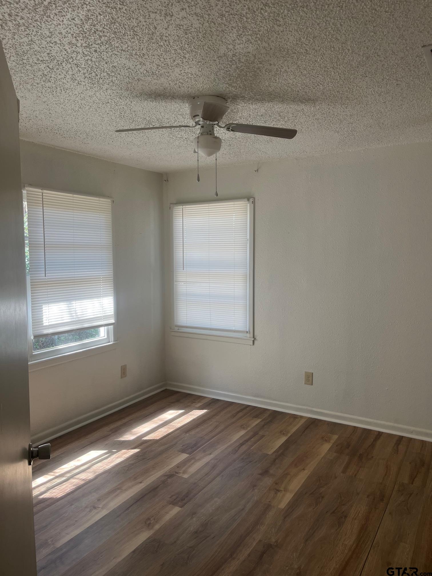 700 West 2nd Street Tyler, TX 75701 - Photo 6 of 10 an empty room with windows and ceiling fan