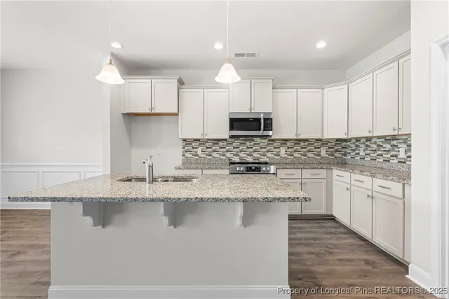 a large kitchen with granite countertop a sink a counter top space appliances and cabinets
