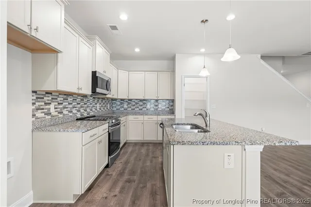 a kitchen with kitchen island granite countertop a sink stove and cabinets