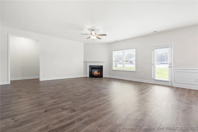 an empty room with wooden floor ceiling fan and windows