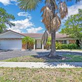 a front view of a house with a garden and a tree
