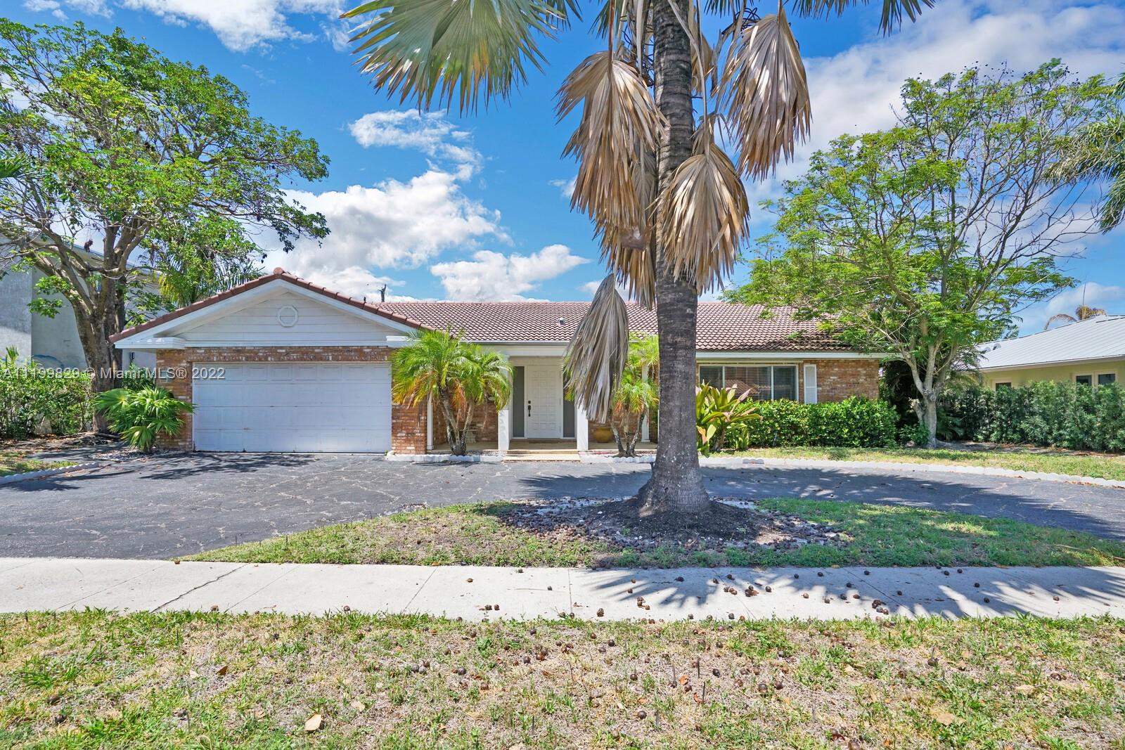 a front view of a house with a garden and a tree