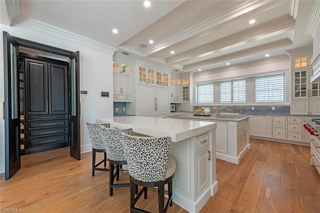 140 3rd Avenue South Naples, FL 34102 - Photo 10 of 46 a kitchen with stainless steel appliances granite countertop a stove top oven a sink dishwasher and a refrigerator with wooden floor