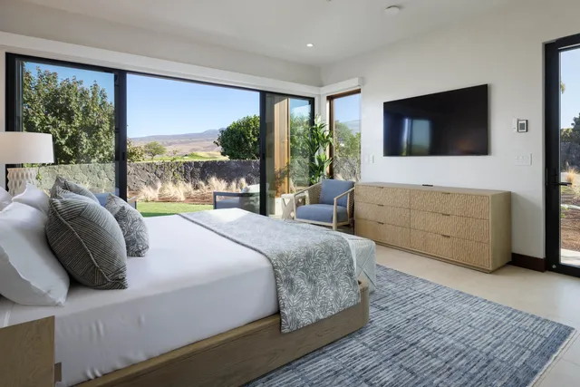 a bedroom with a large bed and a flat tv screen on dresser