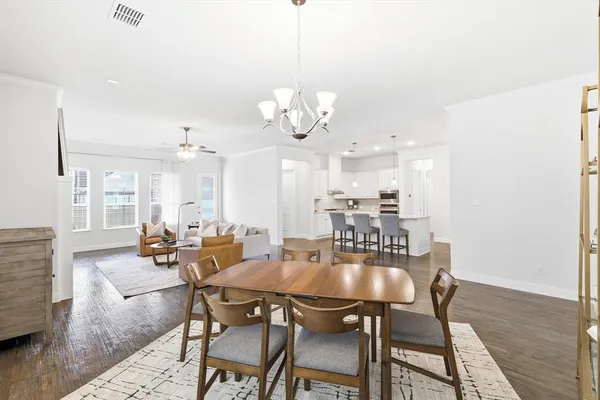 a dining room with wooden floor a chandelier a wooden table and chairs