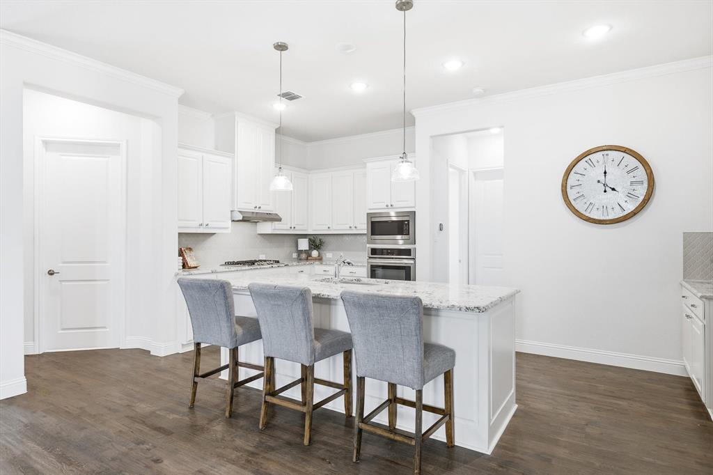 5409 Welsh Street Denton, TX 76226 - Photo 13 of 31 Kitchen featuring white cabinetry, tasteful backsplash, hanging light fixtures, an island with sink, and gas cooktop.