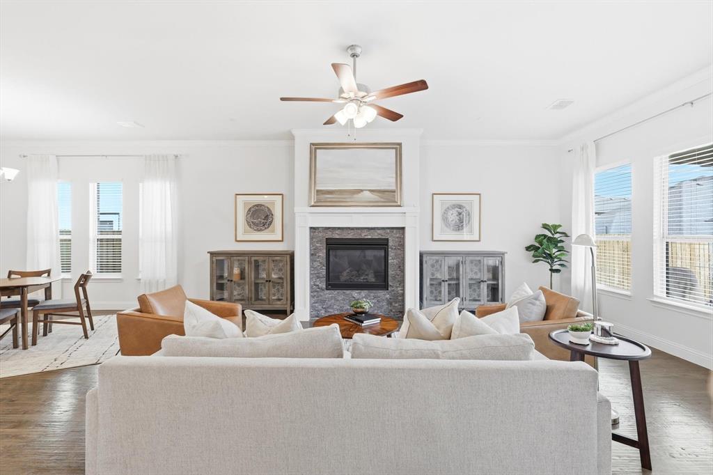 5409 Welsh Street Denton, TX 76226 - Photo 3 of 31 Living area featuring dark wood finished floors, ornamental molding, plenty of natural light, a high end fireplace, and ceiling fan