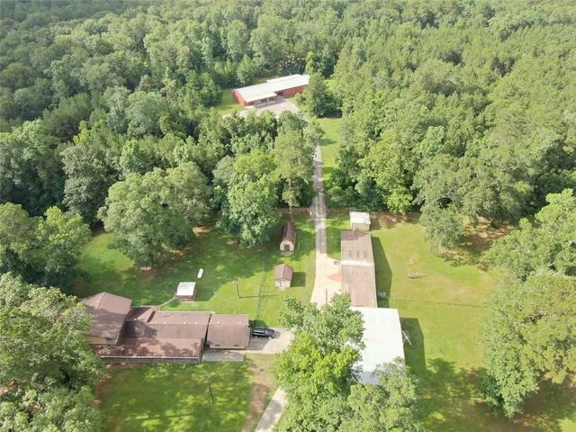 an aerial view of residential house with outdoor space and trees all around