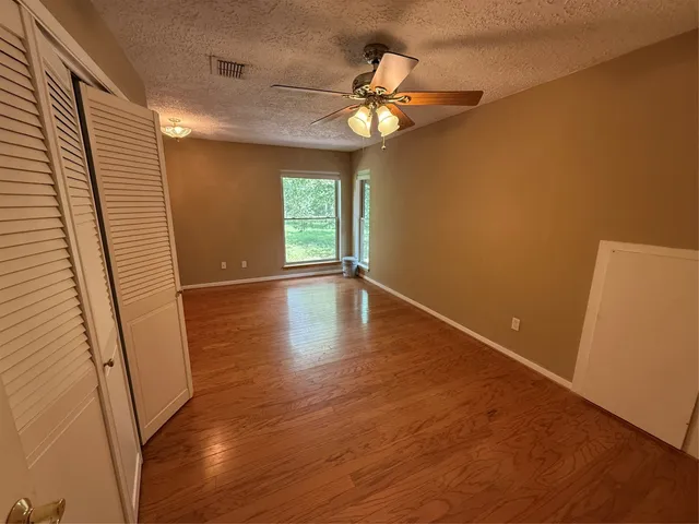 an empty room with wooden floor and windows