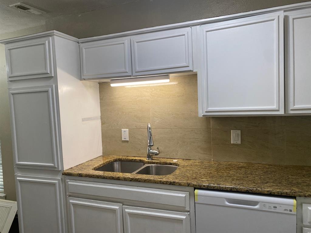 13652 Flagstone Lane Dallas, TX 75240 - Photo 4 of 15 Kitchen with white dishwasher, white cabinetry, dark stone counters, and decorative backsplash