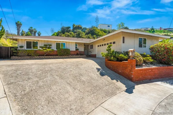 a front view of a house with a yard and potted plants