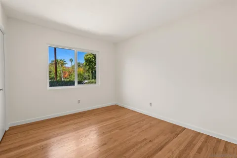 an empty room with wooden floor and window