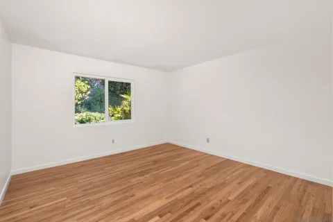 an empty room with wooden floor and window