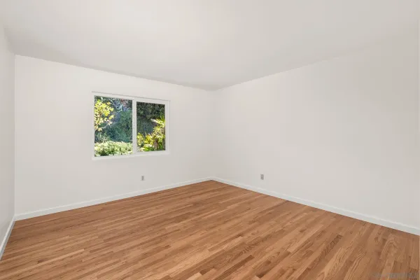 an empty room with wooden floor and window