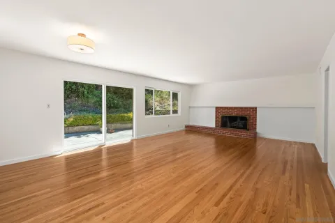 a view of empty room with wooden floor and fireplace