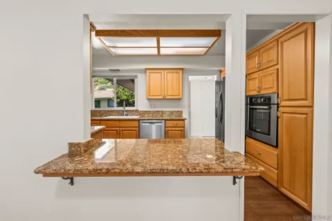 a kitchen with kitchen island granite countertop wooden cabinets and a refrigerator