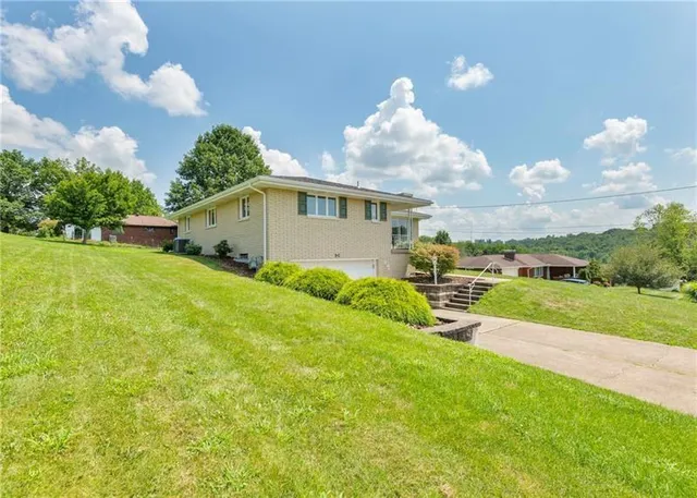 a view of a house with a yard and table and chairs under an umbrella