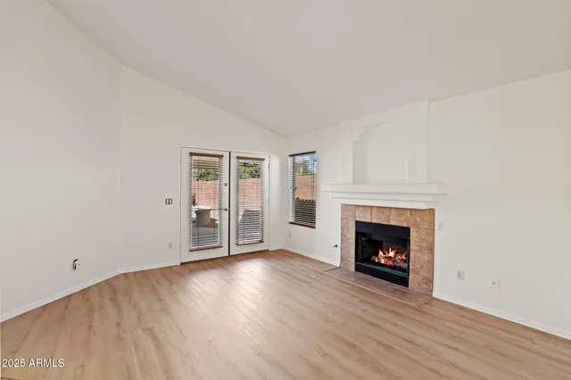 a view of an empty room with wooden floor fireplace and a window