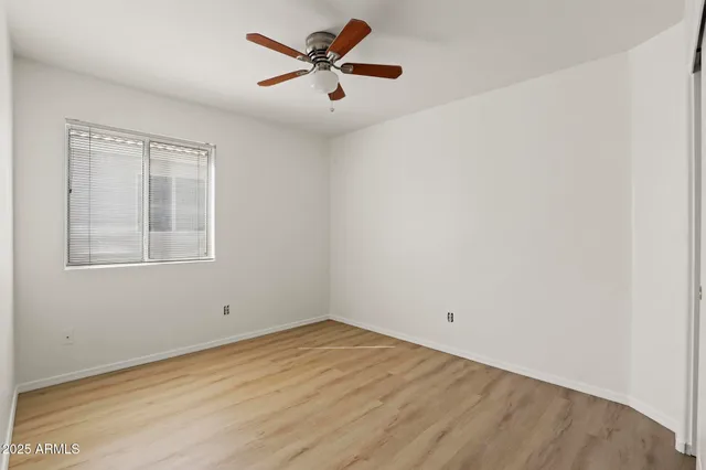 an empty room with a window and a fan