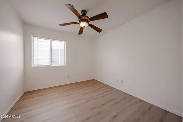an empty room with wooden floor ceiling fan and window