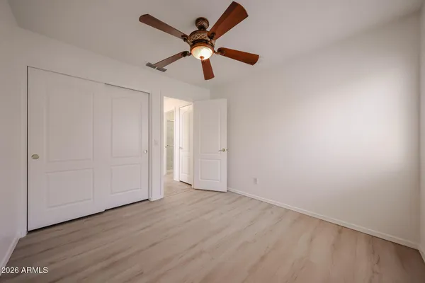 an empty room with wooden floor chandelier fan and windows