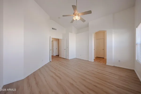 an empty room with wooden floor and fan