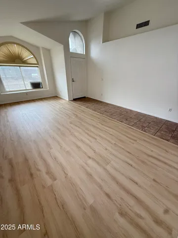 an empty room with wooden floor and mirror