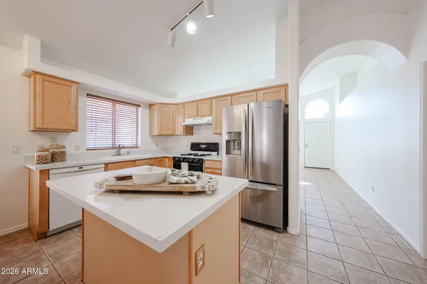 a kitchen with stainless steel appliances kitchen island granite countertop a sink a stove a refrigerator cabinets and a window