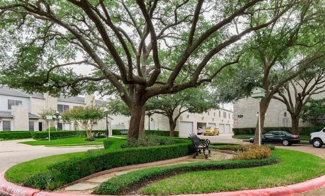 a view of a white house in a big yard with palm trees